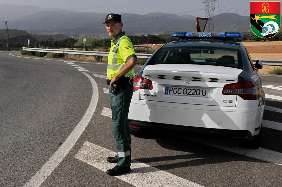 Agente de la Guardia Civil de Tráfico realizando control en carretera junto a vehículo oficial