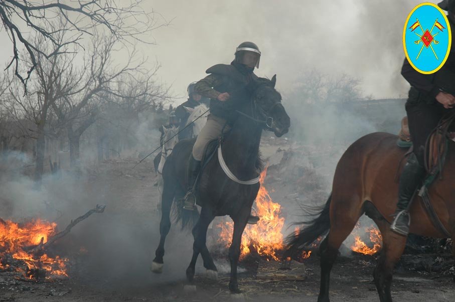 Guardias civiles montados a caballo actuando en zona con fuego y humo durante una intervención.