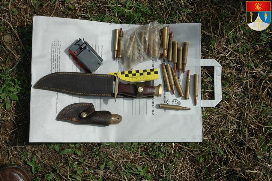Cuchillos, cargador y cartuchos de rifle incautados, dispuestos sobre una bolsa de recogida de muestras