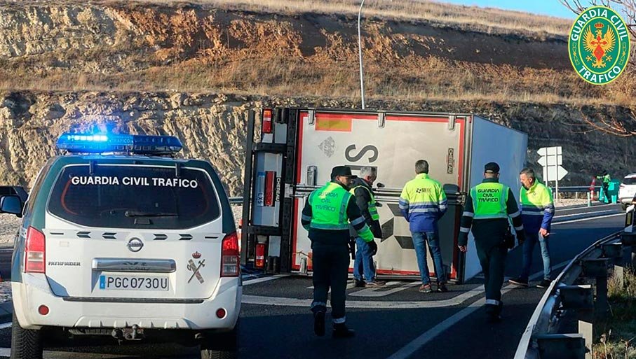 Agentes de la Guardia Civil de Tráfico atendiendo un accidente con un camión volcado en la calzada