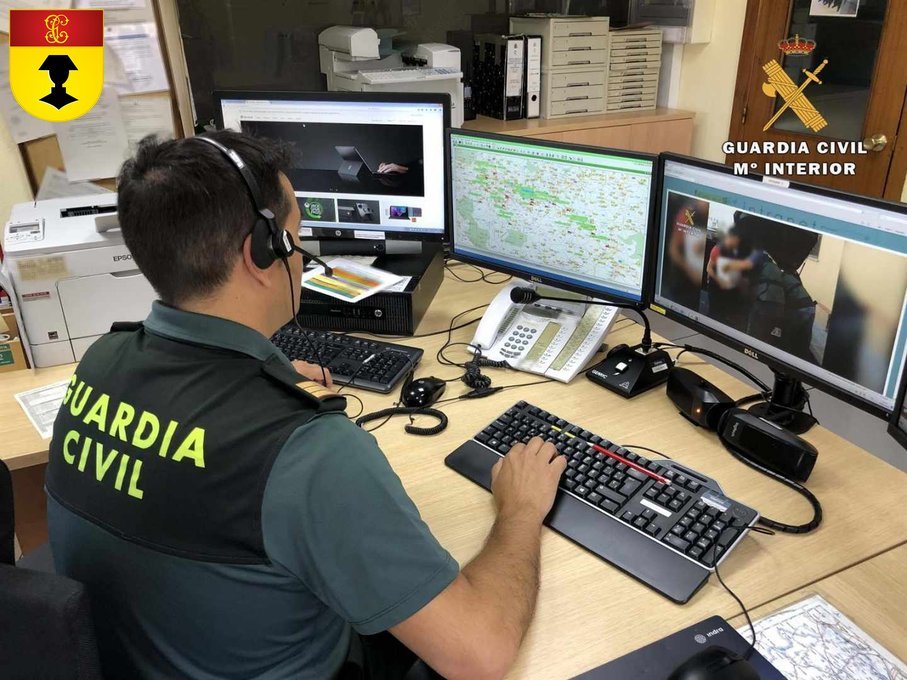 Guardia civil con auriculares trabajando ante varios monitores en su puesto de oficina