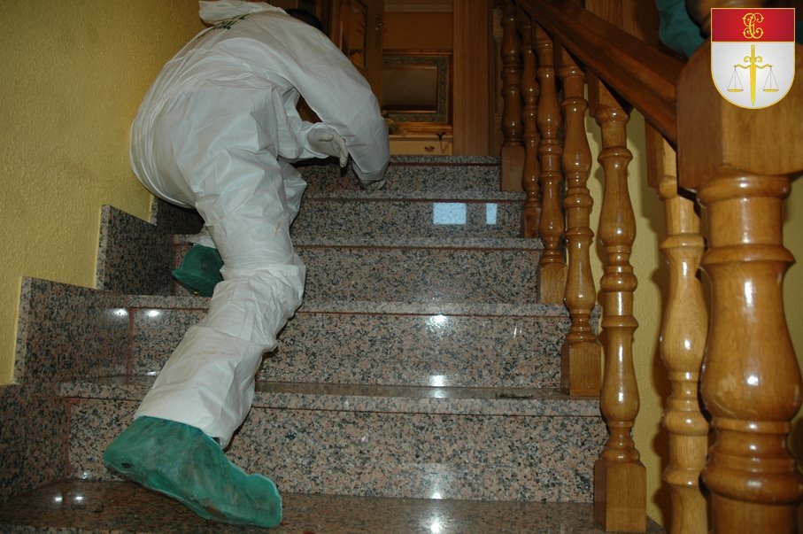 Especialista de Policía Judicial con traje de protección realizando una inspección ocular en una escalera