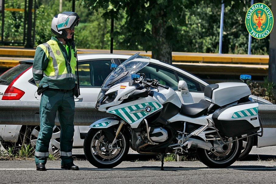 Motorista de la Agrupación de Tráfico de la Guardia Civil junto a su motocicleta BMW en el arcén