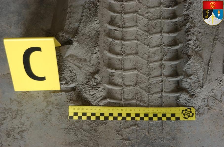 Huella de rodada de un neumático en el suelo, con testigo métrico "C" y regla de escala